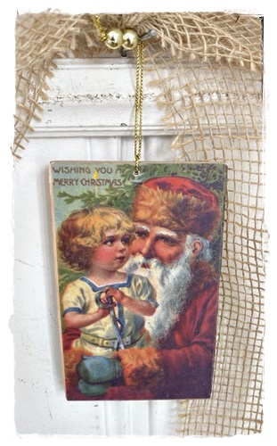 Postcard van hout aan goudkleurig koordje 13 x 8 cm. met victoriaanse afb. Santa en Eef met glittertjes