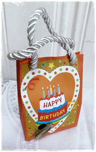 Muziektasje Happy Birthday met opwindsleutel. afm. 9,5 x 6,5 x 3,5/4 kleur oranje