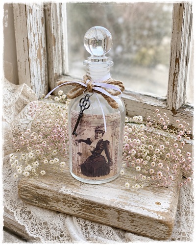 Lief decoratieflesje van 17 cm. groot met afbeelding victoriaanse dame. bovenaan een strikje met sleuteltje